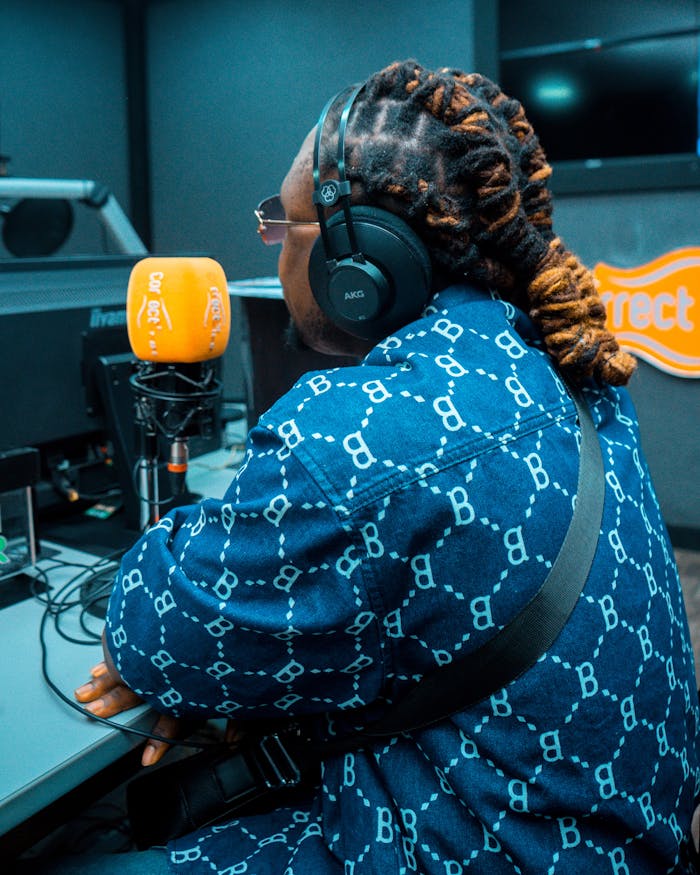 Person wearing headphones speaking into a studio microphone.